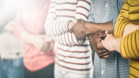 People of diverse backgrounds hold hands in a chain, symbolizing unity and teamwork.