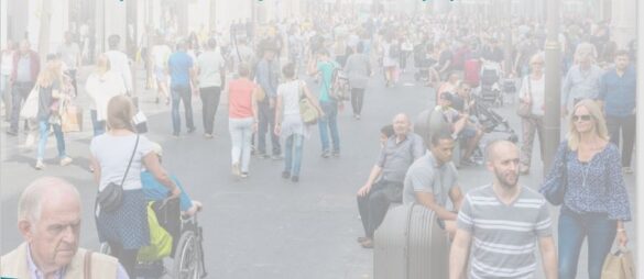 Crowded urban street with pedestrians walking and carrying bags and luggage.