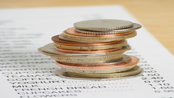 Stack of mixed coins balanced on a printed receipt, illustrating expenses or budgeting