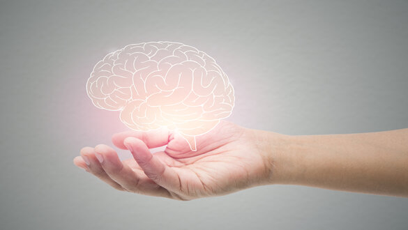 A hand cupping a glowing, outlined brain symbolizing brain health or mental power.